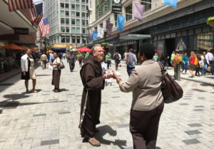 A Franciscan Friar distributes St. Anthony's Blessed Bread to a community member on the Feast of St. Anthony